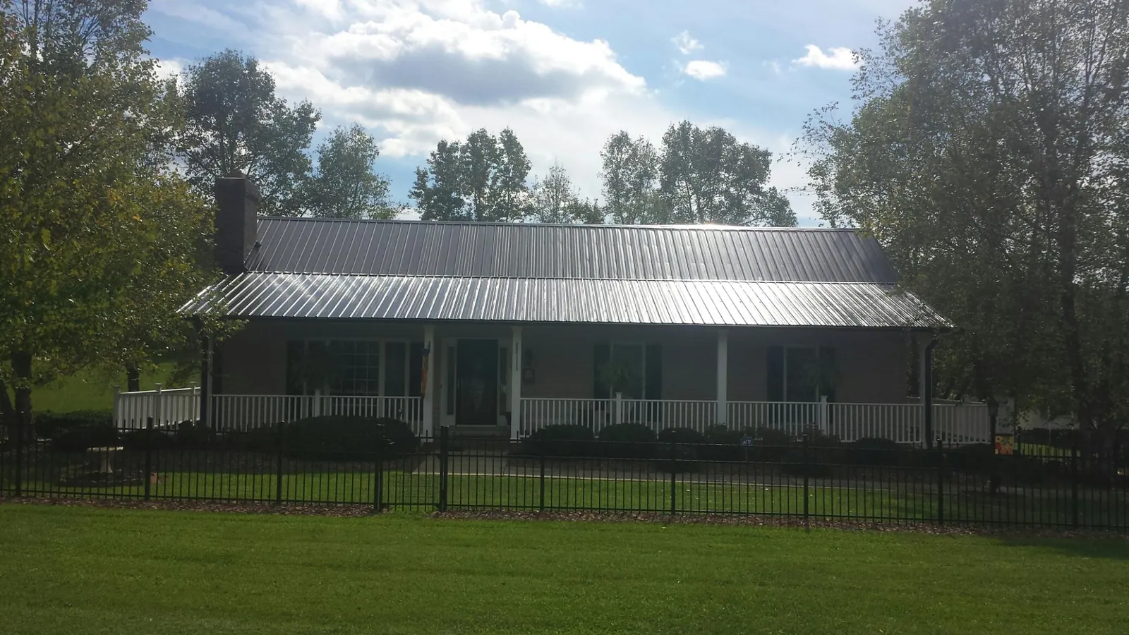 Gray metal roof on a brick ranch with a full width front porch — Gutter Guard Installation work by our crew in West Union